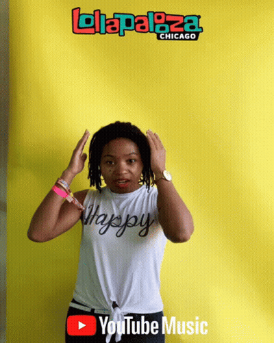 A Woman Is Standing In Front Of A Yellow Background That Says ' Lolapaloza Chicago ' On It GIF