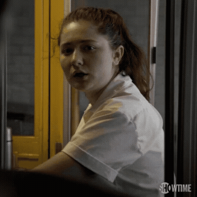 A Woman Is Standing In Front Of A Yellow Door With Showtime Written On The Bottom GIF