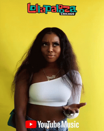 A Woman Is Standing In Front Of A Yellow Wall That Says Lolapaloza Chicago GIF