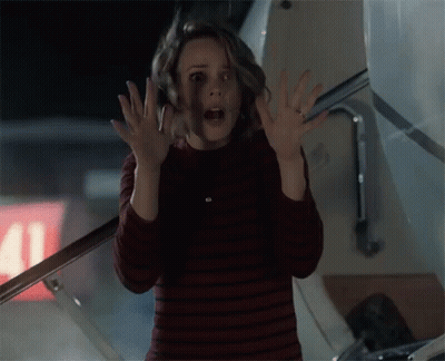 A Woman Is Standing In Front Of An Airplane With Her Hands Up In The Air . GIF