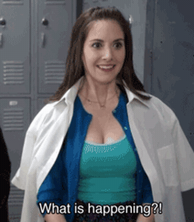 A Woman Is Standing In Front Of Lockers And Smiling While Asking What Is Happening . GIF
