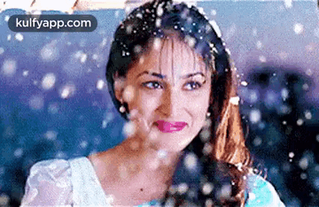A Woman Is Standing In The Snow And Smiling . GIF