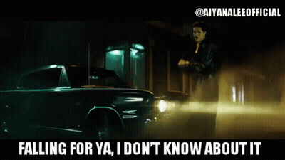 A Woman Is Standing Next To A Car That Says " Falling For Ya I Don 'T Know About It " GIF