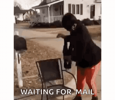 A Woman Is Standing Next To A Chair In Front Of A Mailbox And Waiting For Mail . GIF