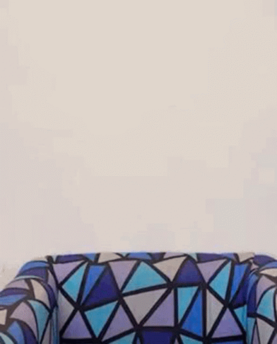 A Woman Is Standing Next To A Colorful Couch With A Geometric Pattern . GIF