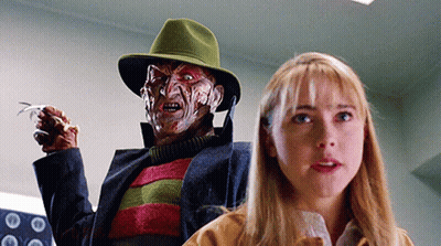 A Woman Is Standing Next To A Freddy Krueger Doll GIF