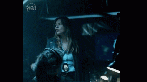 A Woman Is Standing Next To A Man In A Dark Room With A Planeta Logo In The Corner . GIF