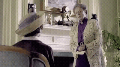 A Woman Is Standing Next To A Man In A Living Room Holding A Piece Of Paper . GIF