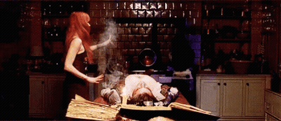 A Woman Is Standing Next To A Man Laying On A Table With A Book Open On It . GIF