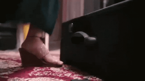 A Woman Is Standing Next To A Suitcase On A Carpet . GIF