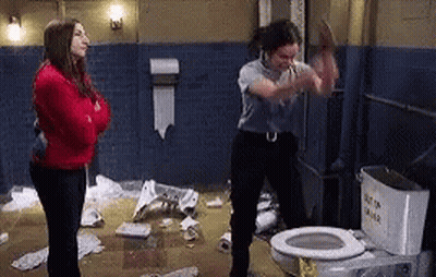 A Woman Is Standing Next To A Toilet In A Messy Bathroom . GIF