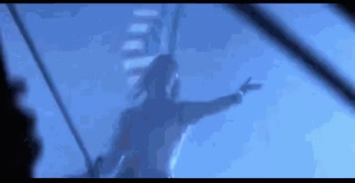 A Woman Is Standing On A Boat In The Water With Her Arms Outstretched . GIF