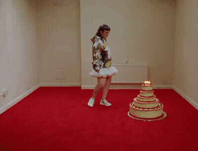 A Woman Is Standing On A Cake That Has Candles On It GIF