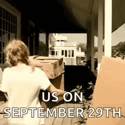 A Woman Is Standing On A Porch Holding A Box With The Date September 29Th On It . GIF