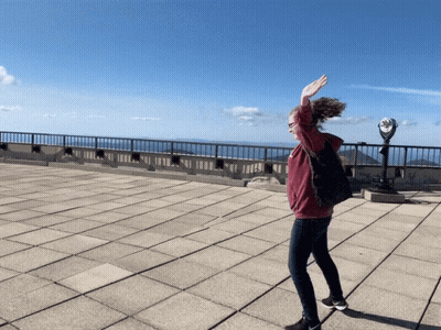 A Woman Is Standing On A Rooftop With Her Arms Outstretched GIF