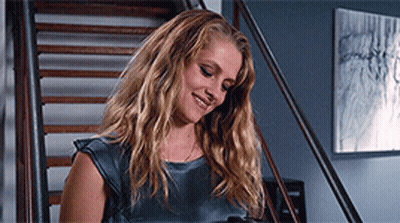 A Woman Is Standing On A Set Of Stairs And Smiling GIF