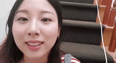 A Woman Is Standing On A Set Of Stairs Smiling . GIF