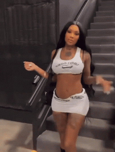 A Woman Is Standing On A Set Of Stairs Wearing A Crop Top And Skirt . GIF