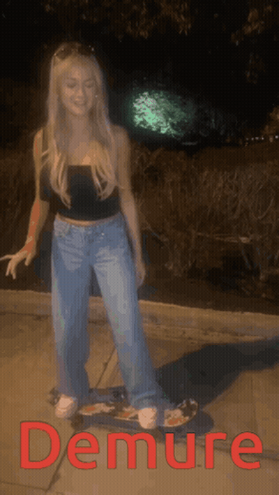A Woman Is Standing On A Skateboard With The Word Demure In Red Letters GIF