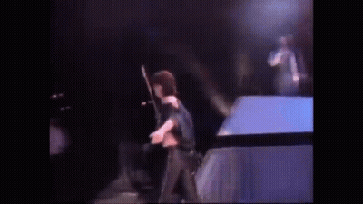 A Woman Is Standing On A Stage Holding A Microphone . GIF