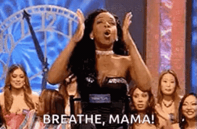 A Woman Is Standing On A Stage With Her Hands In The Air And A Group Of Women Behind Her . GIF