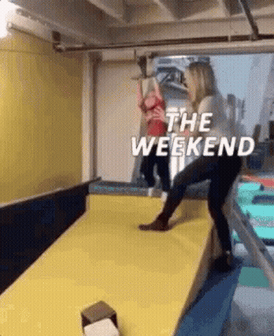 A Woman Is Standing On A Yellow Mat In A Gym With A Child . GIF