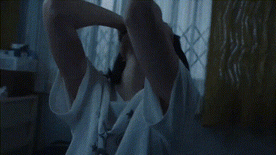 A Woman Is Standing On An Escalator With Her Hands On Her Head GIF