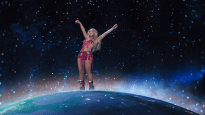 A Woman Is Standing On Top Of A Globe With Her Arms In The Air GIF
