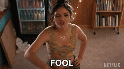 A Woman Is Standing With Her Hands On Her Hips And The Word Fool Is On The Floor GIF
