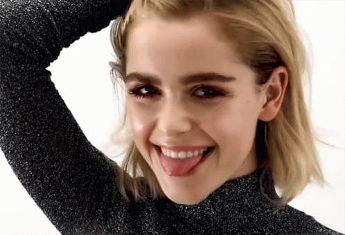 A Woman Is Sticking Her Tongue Out And Smiling GIF