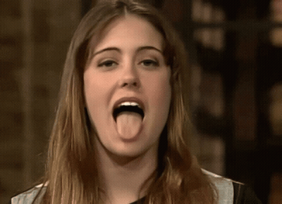 A Woman Is Sticking Her Tongue Out In A Close Up GIF