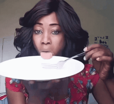 A Woman Is Sticking Her Tongue Out While Holding A Plate With A Sausage On It GIF