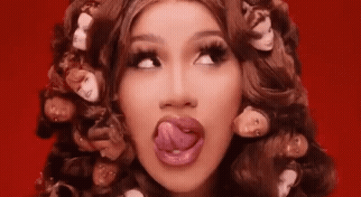 A Woman Is Sticking Her Tongue Out While Wearing A Wig With Heads On It . GIF