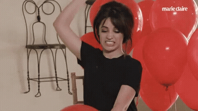 A Woman Is Surrounded By Red Balloons With Marie Claire Written On The Balloons GIF