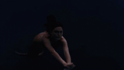 A Woman Is Swimming In A Body Of Water GIF