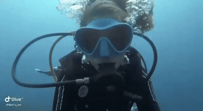 A Woman Is Swimming In The Ocean Wearing A Scuba Mask . GIF