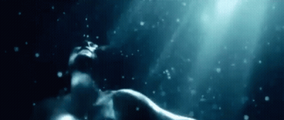 A Woman Is Swimming Underwater In The Ocean With Bubbles Coming Out Of Her Mouth . GIF