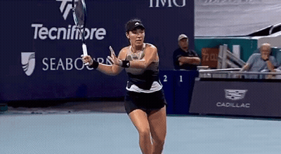 A Woman Is Swinging A Tennis Racquet On A Tennis Court In Front Of A Sign That Says Tecnifibre GIF