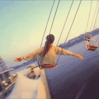 A Woman Is Swinging On A Merry Go Round At A Carnival GIF