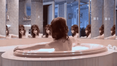 A Woman Is Taking A Bath In A Jacuzzi In Front Of A Mirror . GIF