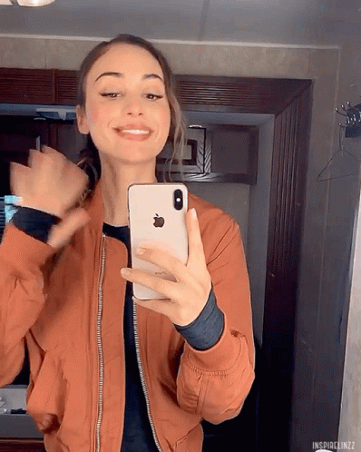 A Woman Is Taking A Picture Of Herself With Her Iphone GIF