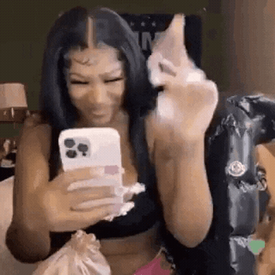 a woman is taking a picture of herself with her phone while sitting on a bed .