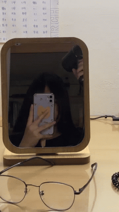 A Woman Is Taking A Selfie In Front Of A Mirror With A Calendar Behind Her That Says March GIF