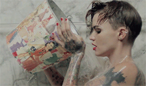 A Woman Is Taking A Shower And Holding A Bucket With A Picture On It GIF