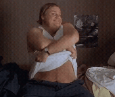 A Woman Is Taking Off Her Shirt And Smiling GIF