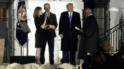 A Woman Is Taking The Oath Of Office In Front Of A Group Of People Including Donald Trump . GIF