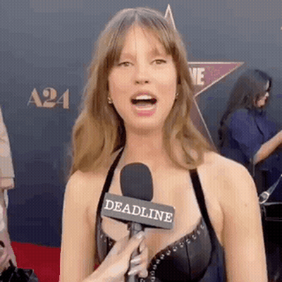 A Woman Is Talking Into A Microphone On A Red Carpet At An Event . GIF
