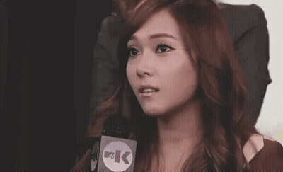 A Woman Is Talking Into A Microphone While Making A Funny Face . GIF