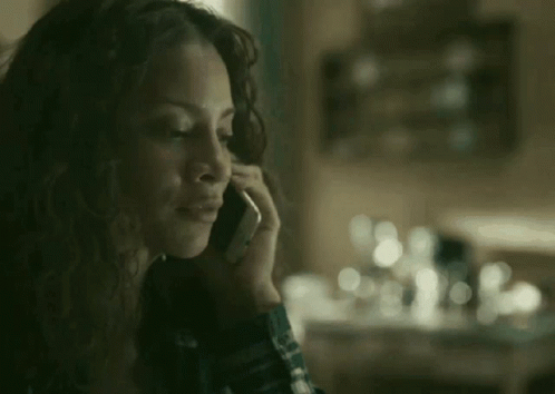 A Woman Is Talking On A Cell Phone In Front Of A Table . GIF