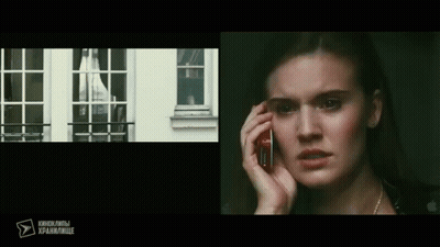 A Woman Is Talking On A Cell Phone In Front Of A Window With Russian Writing On The Bottom GIF
